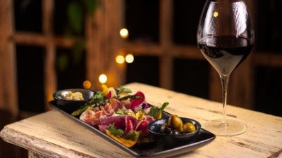 Tabla de antipasto con embutidos, aceitunas y vino tinto en Parole