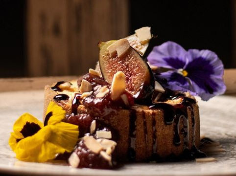Postre de chocolate con higo, almendras y flores comestibles en Parole