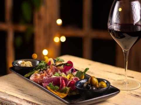 Tabla de antipasto con embutidos, aceitunas y vino tinto en Parole